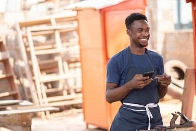 a smiling man holding a phone and atm card how to open a dollar account in Nigeria